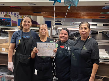 Irrene Andrade shows her STAR Award as she stands with the Child Nutrition Team