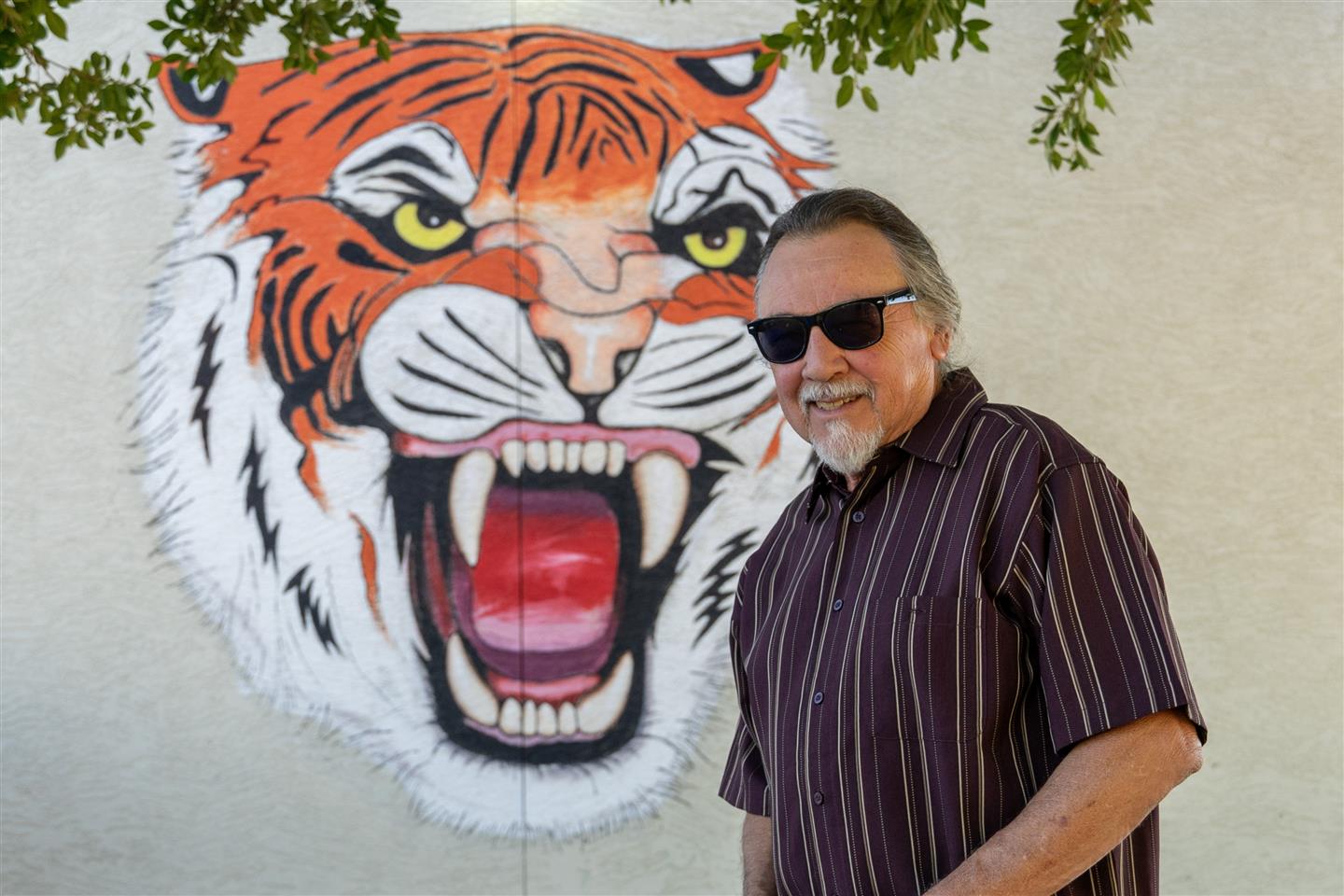 Artist José Andrés Girón poses with the tiger mural he painted at Lowell Elementary School